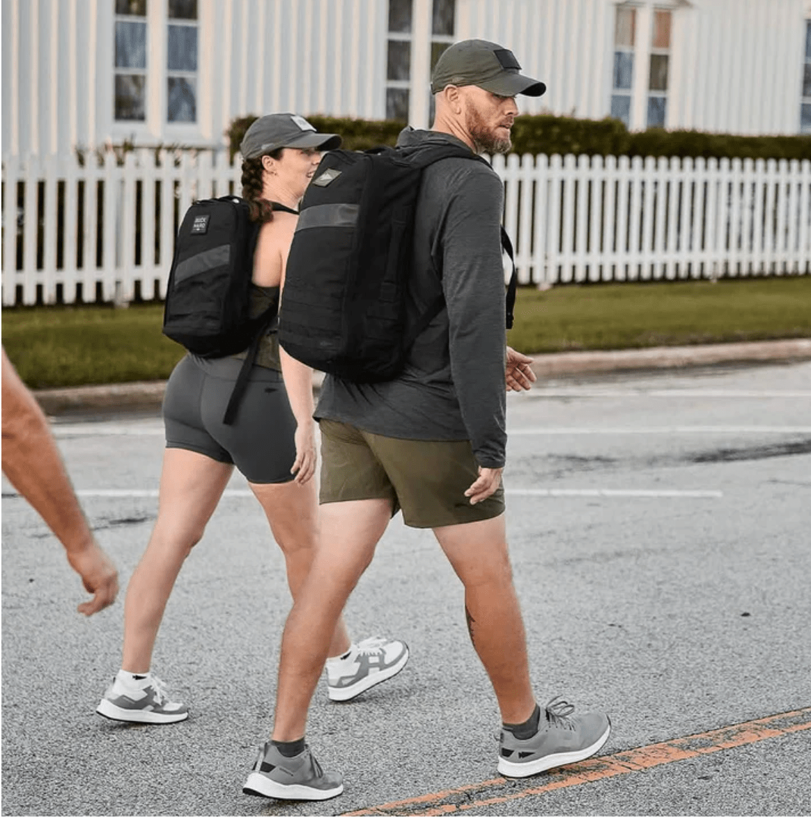Two people walking down a street wearing backpacks.